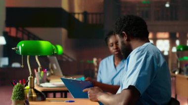 Geleceğin hemşireleri bir üniversite kütüphanesinde anatomi dersi alıyor, dersleri gözden geçiriyor ve sınavlara hazırlanıyor. Siyahi tıp fakültesi öğrencileri tıp eğitimi için birlikte çalışıyorlar. Kamera B.