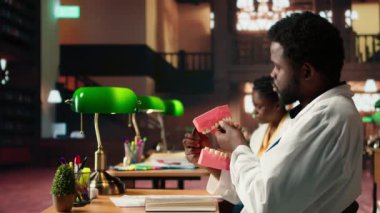 Diş eğitimine odaklanan zenci erkek öğrenci sahte bir insan çenesi kullanarak ağız hijyeni ve stomatoloji eğitimi alıyor. Üniversite kütüphanesinde dişçilik sınavına hazırlanan genç bir yetişkin. Kamera A.