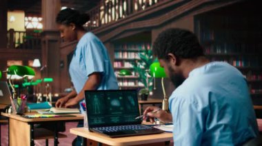 Tıp fakültesi öğrencisi anatomi araştırma kağıtlarından kişisel notlar alıyor, tıp kariyeri için sağlık yöntemleri okuyor. Kampüs veritabanındaki kitapları kullanan bir erkek öğrenci. Kamera A.