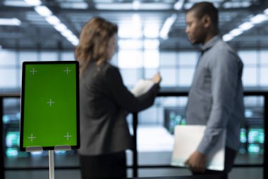 Bulanık arkaplan analizi yapan veri merkezi teknisyenlerinin önündeki model cihazına odaklan. Yeşil ekran tabletini, sorunsuz işlemleri sağlayan sunucu merkezi işçilerinin yanına kapat