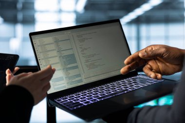 Bilgisayar kullanarak veri merkezindeki yazılım geliştiricileri ölçümleri analiz ediyor, depolama hacmini optimize ediyorlar. Bilgi işlem uzmanları dizüstü bilgisayar kullanarak, tartışarak, sorunsuz işlemleri güvence altına alarak sunucu merkezi tesisinde çalışıyorlar.