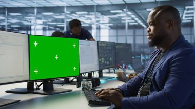 Afro-Amerikan veri merkezi yönetimi, şirket ağ altyapısını korumak için PC 'yi kullanıyor. Sunucu çiftliğinde çalışan bir adam yeşil ekran bilgisayarla optimal sistem performansı sağlıyor