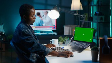 Oturma odasındaki tele-işçi iş ortaklarından gelen e-postaları cevaplamak için krom anahtar dizüstü bilgisayar kullanıyor. İzole ekran aygıtı klavyesinde yazan, dairedeki görevleri çözen uzak çalışan