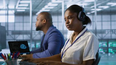 Veri merkezi mühendisi kulaklık takarak şarkıların keyfini çıkarıyor, şirket ağ altyapısını koruyor. Sunucu merkezindeki kadın müzik dinlerken ideal sistem performansını sağlarken, kamera A