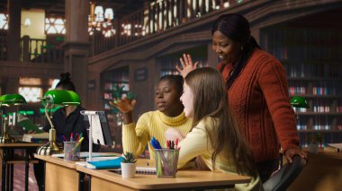 İlkokul öğrencileri ve öğretmenleri kütüphane masasından web kamerasıyla diğer sınıf arkadaşlarına bağlı bir çevrimiçi kursa katılıyorlar. Sanal Webinar tartışması. Kamera A.