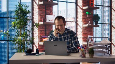 Adam ofis masasında dizüstü bilgisayarla oturmuş, ekrandaki e-postaları kontrol ederken telefona cevap veriyor. Gelen kutusundaki mesajları okurken iş yerinden bir arkadaşla telefon görüşmesi yapan işçi, kamera A