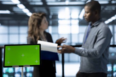 Bulanık arka planda veri merkezi teknisyenleri tarafından kullanılan model tableti donanım tanılarını gözden geçiriyor. Ayar aygıtlarını ayarlayan çalışanların kullandığı izole ekran cihazını kapat