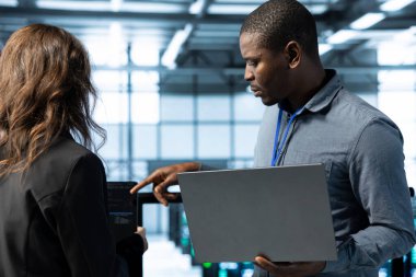 Veri merkezindeki iş arkadaşları enerji kullanımını ayarlamak için dizüstü bilgisayar kullanırlar. UPS ayarlarını denetlemek için dizüstü bilgisayar kullanan sunucu odası bilişim uzmanı, ekipmanların bakımını yapıyor