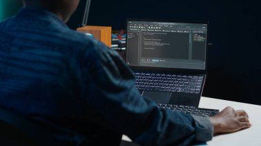 Yazılım geliştiricisi Java programlama dillerini kullanarak daire ofisindeyken laptop ekranına kod yazar. Programcı, evden ve kamera A 'dan çalışırken veri tabanı hatalarını düzeltmeye çalışıyor