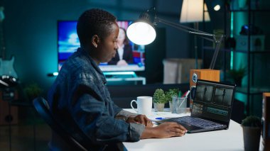 Uzaktan çalışan videograf, özel yazılım uygulamaları kullanarak video montajı yapıyor. Afrika kökenli Amerikalı video editörü dizüstü bilgisayardaki kurgu araçlarını kullanarak ofisteki film projesini, kamera A 'yı kesti.