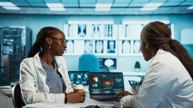 Afrika kökenli Amerikalı doktor ve hasta bir tesiste tıbbi danışmanlık yapıyorlar ve hastalıkların önlenmesi için sağlık hizmetleri öneriyorlar. Tedavi planlama için tıbbi raporlar. Kamera B.