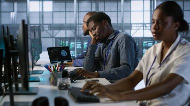 Yorgun veri merkezi mühendisi esniyor, şirket ağ altyapısını korurken uykusuzluk çekiyor. Sıkılmış sunucu merkezi çalışanı yorgun hissediyor, uyanık kalmaya çalışıyor, kamera A