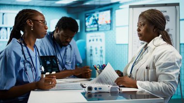 Afrika kökenli Amerikan tıp personeli, bir ofiste danışma öncesinde gelişmiş teknoloji araçlarıyla uzmanlıklarını birleştiriyor. Harika sağlık hizmetleri sağlamak için ekip çalışması. Kamera B.