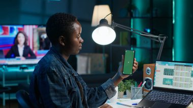 Merkez ofisteki telgraf çalışanı dizüstü bilgisayardaki istatistikleri kontrol ediyor, yeşil ekran akıllı telefonundaki verilerle karşılaştırıyor. Elinde model cep telefonu olan kişi, şirketin gelir numaralarını analiz ediyor.