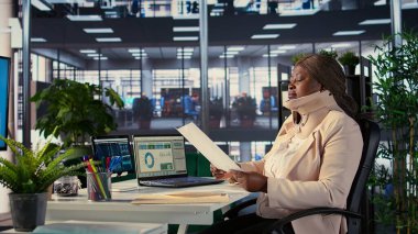 Servikal tasmalı CEO aylık raporlara göre çalışanların performanslarını değerlendiriyor, yaralanmadan sonra tıbbi boyun köpüğünü giyerken genel analizler yapıyor. Yönetmen trendleri inceliyor. Kamera B.