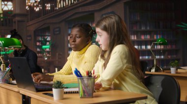 Kütüphanedeki ilkokul öğrencileri çevrimiçi bir seminer sırasında, teknolojiyi eğitimci ve sınıf arkadaşlarıyla etkileşimli sanal sohbet için kullanıyorlar. Web konferansı üzerinden uzak ders. Kamera A.