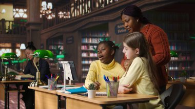 Sınıf arkadaşları öğretmenle okul takımı projesi yaparken videoda Webinar 'ı arıyor ve video bağlantısındaki diğer meslektaşlarıyla kütüphane kitapları ve materyaller hakkında tartışıyorlar. Kamera A.