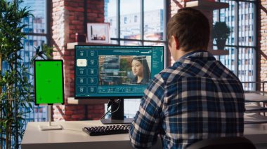 Yeşil ekran tabletinde video üretici modeller için metnin nasıl kullanılacağını öğrenmek isteyen bir adam. Ofisteki adam yapay zeka programı ve A kamerasıyla ilgili video rehberini izliyor.