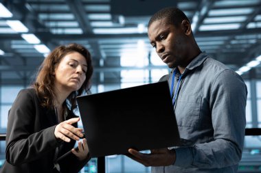 Sunucu çiftliğinde çalışan mühendislerden oluşan bir ekip verileri analiz etmek için dizüstü bilgisayar kullanıyor. Veri merkezindeki altyapıyı inceleyen ekip çalışanları, sistem bütünlüğü ve güvenliğini sağlıyorlar