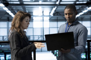 Veri merkezi programcısı ve meslektaşı dizüstü bilgisayar kullanıyor, güvenlik denetimleri yapıyor, hataları önlüyor. Bilgi işlem görevlileri güvenlik duvarı kurallarını gözden geçirmek için işbirliği yapıyor, olay ayrıntılarını kaydediyor, konuşuyor