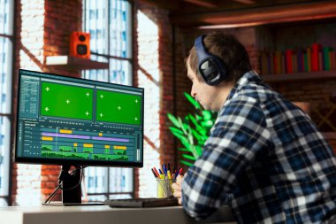Yeşil ekrandaki ham görüntüleri parlatmak ve ses kalitesini arttırmak için kulaklık takan video editörü. Videograf, klipleri modelleme bilgisayarında ayarlıyor, filme ses efektleri uyguluyor