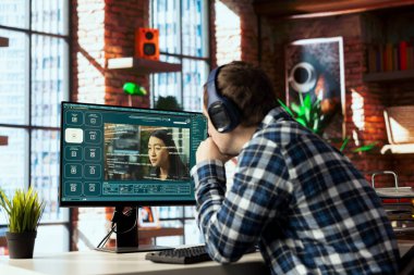 Merkez ofiste müzik dinleyen ve üretici yapay zeka GPT videoları kullanan bir adam. Kulaklık takan kişi yapay zeka asistanı kullanır.