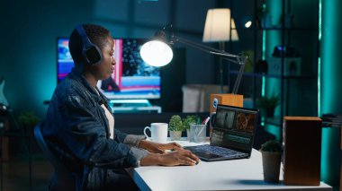 Video editörü ses efektleri ekliyor. Ev stüdyosunda çalışıyor. Ses kalitesini ölçmek ve geliştirmek için kulaklık kullanan kameraman, profesyonel yazılım ve kamera A ile klipleri düzenliyor