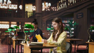 Okul kütüphanesinde kitap okumaya dalmış, akademik dersleri ve diğer sınıf ödevlerine hazırlanırken edebiyat ve bilgiye odaklanmış genç bir kız. Kamera A.