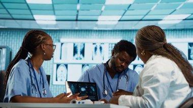 Doktorla sonuçları analiz eden, modern bir ofiste takım çalışması, profesyonel eğitim ve bakım yönetimi konularını vurgulayan bir grup önlük uzmanı. Tıbbi personel araştırma yapıyor. Kamera A.