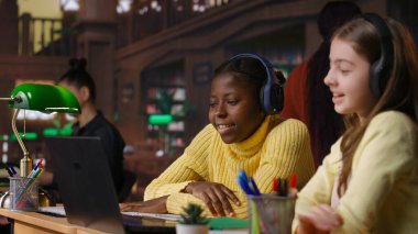 Öğrenciler ders kitaplarındaki ders kitaplarının yanında ders çalışmaya hazırlanıyor ve fikirler yazıyor, kütüphanede ödev olarak yansıtıcı bir makale hazırlıyorlar. Okul ödevi. Kamera A.