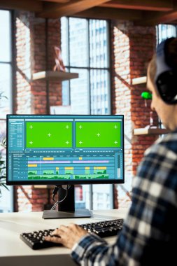 Video düzenleyici, video montaj yaparken kullanılacak anahtar çerçeveleri seçiyor, krom anahtar bilgisayarda evden çalışıyor. İzole edilmiş ekrandaki film projesinin görüntülerini düzenlemek için fareyi kullanan adamı kapat