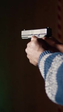 Dikey video atış poligonu müşterisi tabancayla ateş edip etmediğini kontrol ediyor. Atış poligonunda silah kullanmayı öğrenen, vurulan hedefleri analiz eden kişiye yaklaş.