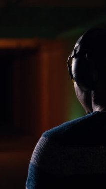 Gülümseyen bir adamın atış talimi yaparken çekilmiş dikey video görüntüsü, düzgün tabanca tutma görgü kurallarını öğrenme ve eğlenme. Neşeli silah meraklısı silahlarla pratik yapan, koruyucu giyimli.