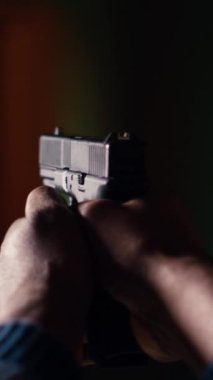 Dikey video çekim galerisi müşterisi kağıt hedefleri vurmak için tabanca kullanıyor. Kapalı alan atış poligonu tesisinde güvenlik ekipmanı takan birini yakın plan çekiyoruz. Boğa avlıyoruz.