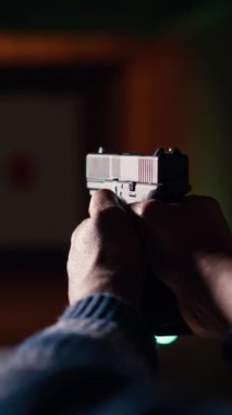 Atış poligonunda ateşli silah kullanan dikey video adam hareketli hedef sonuçlarına bakıyor. Rekabetçi atış sporu, keskinleştirme becerileri, kontrol puanları için kişi eğitimini kapat