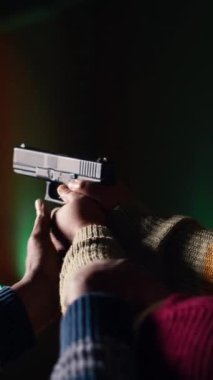 Dikey video çekimi galerisi çalışanı öğrencisine silah tutmayı öğretiyor, yakın çekim. Atış menzili uzmanı, ateşli silahlarla yüksek seviyede uzmanlaşmayı öğrenen kadınlara rehberlik ediyor.