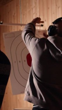 Dikey Videocu tüfeği tutuyor, arkadaş grubunun yanında eğlence amaçlı atış tecrübesinin tadını çıkarıyor. Atış poligonunda ve kamerada silahlarla çalışan insanlar.