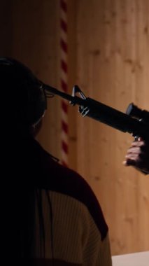 Atış poligonunda işitmeyi korumak için kulaklık takan arkadaşlardan oluşan dikey bir video grubu. İnsanlar silah dolduruyor, silah seslerinden zarar görmemek için güvenlik teçhizatı kullanıyor.