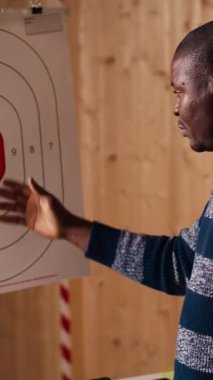 Dikey video atış poligonu güvenlik görevlisi bir grup arkadaşa hedef puanı sistemini açıklıyor. Afrika kökenli Amerikalı atış poligonu uzmanı hedef kitle sistemini öğretiyor ve endüstriyi tartışıyor.