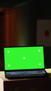 Atış menzilinde, hedefleri başarılı bir şekilde vuran adamın yanındaki dikey video yeşil ekran laptop. Eğitmen tarafından hedef tahtası, kamera ve kameraya isabet ettirdiği için tebrik edilen kişinin yanındaki maket defteri.