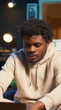 Günümüz oturma odasında otururken dizüstü bilgisayarındaki program ve notları yöneten dikey video genç erkek serbest yazar. Etkileyici bir adam verimli bir tele çalışma seansı için bilgisayara bakar. Kamera B.