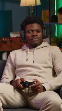 Dairesinde video oyunu oynayan, işten izin gününün tadını çıkaran dikey, neşeli bir adam var. Siyah oyuncu oyun konsolunda online çok oyunculu atıcılarla savaşıyor. Kamera A.