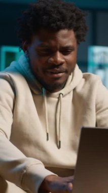 Günümüz oturma odasında otururken dizüstü bilgisayarındaki program ve notları yöneten dikey video genç erkek serbest yazar. Etkileyici bir adam verimli bir tele çalışma seansı için bilgisayara bakar. Kamera A.