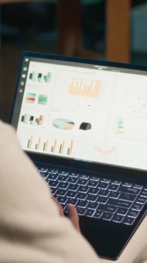 Dikey Video Uzaktan İşçi Muhasebeci bilgisayardaki finansal grafikleri kullanarak matematik hesaplamaları yapıyor, evde çalışıyor. Çatı katında serbest çalışan bir adam defterdeki ekonomik rakamları karşılaştırıyor. Kamera A.