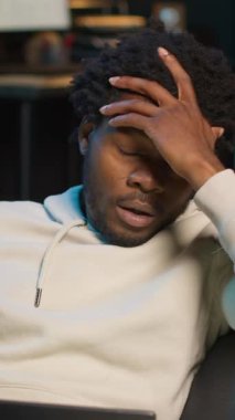 Dikey Video Öz, acıdan ve yüksek ateşten muzdarip bir adam koltukta oturup işini bitirmeye çalışıyor. Siyah erkek duygu sömürücü hasta ve hasta, dizüstü bilgisayar kullanıyor.