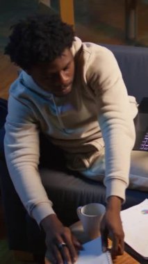 Kanepede oturup analitik araştırma kağıtları okuyan, evinde dizüstü bilgisayarla birden fazla iş yapan dikey video gündelikçisi. İnsan profesyonel ya da kişisel gelişim konularına dalıyor