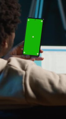 Dikey Video Güvenilir Teknoloji kullanıcısı oturma odasında izole edilmiş bir model görüntüsüne bakıyor. Kanepedeki uzaktan kumandalı işi ile rahatlıyor. Afrikalı Amerikalı mutlu yetişkin internette geziniyor. Kamera A.