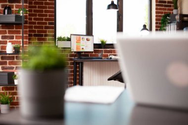 İyi organize edilmiş tuğla duvar odası dizüstü bilgisayarı, masaüstü bilgisayarı, bitki süslemeleri ve ofis malzemeleri içeriyor. Alan iş analizi veya şirket toplantısı için hazırlanarak rahat çalışma alanı sunuluyor.