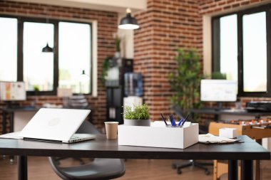 Geniş bir girişim bürosunda, işçiler için modern kurulum sağlayan dizüstü bilgisayar ve iş materyalleri içeren temiz bir masa bulunuyor. İyi örgütlenmiş tuğla duvar işyeri bir sonraki proje ya da şirket araştırması için hazır..