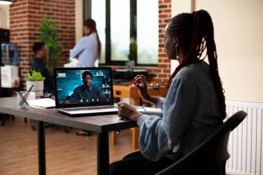 İş kadını ve erkek müvekkil modern ofiste sanal toplantı üzerine gelişme planlarını tartışıyorlar. Kadın girişimci iş adamıyla video konferans çağrısı yapıyor, proje uygulaması üzerine strateji kuruyor.